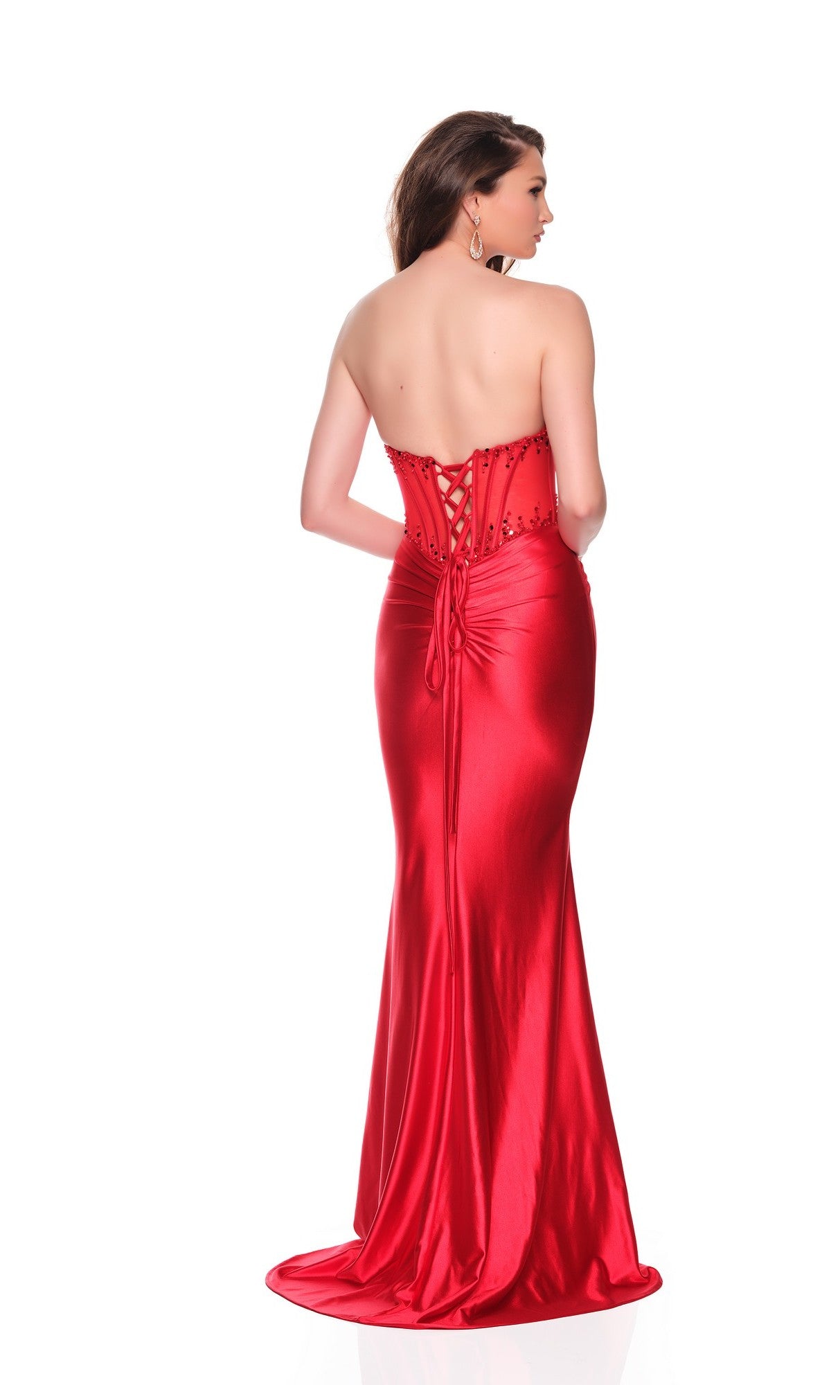 A woman faces away, wearing the Dave and Johnny 12931 long prom dress—strapless, red satin with a lace-up open back and fitted silhouette—against a plain white background.